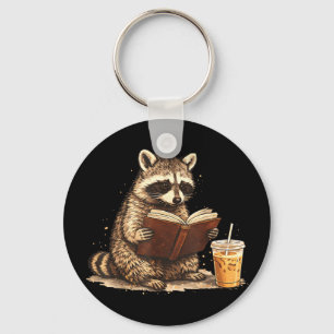 Raccoon drinking iced coffee & reading book keychain