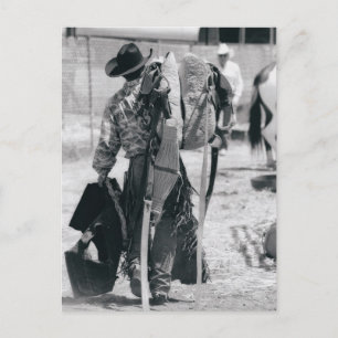 Rear view of cowboy hauling gear postcard