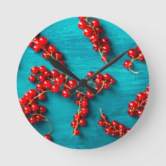 Red currant on blue background. Colorful food desi Round Clock