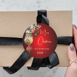 Red gold baubles Christmas Classic Round Sticker<br><div class="desc">For a Christmas party favours or gift wrapping. A red uneven coloured background. Decorated with red and gold baubles and some greenery and a pine cone.  Personalize and add your name,  year.  Text: Merry Christmas</div>