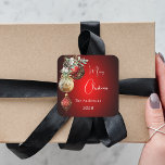 Red gold baubles Christmas Square Sticker<br><div class="desc">For a Christmas party favours or gift wrapping. A red uneven coloured background. Decorated with red and gold baubles and some greenery and a pine cone.  Personalize and add your name,  year.  Text: Merry Christmas</div>