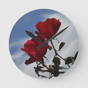 Red Roses Against a Bright Blue Sky Round Clock