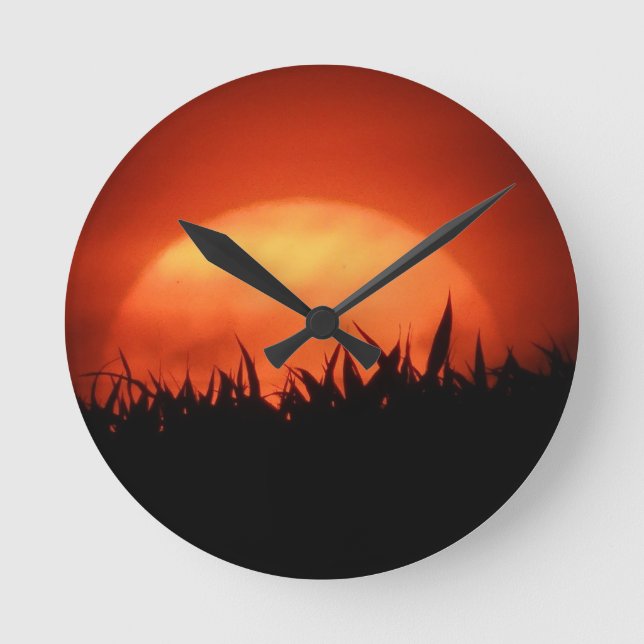 Red sundown behind black grass round clock (Front)