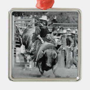 Rider hanging on to bucking bull metal ornament