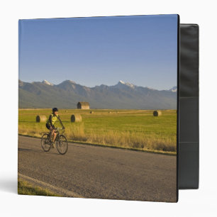 Road bicyclists ride down a back country road binder
