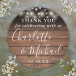 Rustic Wood String Lights Wedding Favour Thank You Classic Round Sticker<br><div class="desc">Rustic signature script wedding favour thank you classic round sticker featuring pretty string lights and signature style names on a wood panels background. Personalize with your special thank you information in chic white typography. Designed by Thisisnotme©</div>