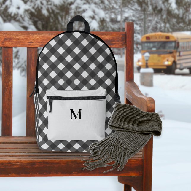Sac À Dos Imprimé Buffalo plaqué noir et gris Motif Monogramme (A backpack with black and white buffalo check pattern and monogrammed silver-gray front pocket)