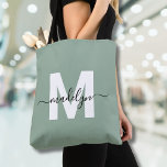 Sage Green Modern Script Name Monogram Tote Bag<br><div class="desc">Personalized Elegant Sage Green Trendy Modern Script Name Monogram Tote Bag. Add a touch of sophistication to your everyday style with this chic tote bag. Featuring a sleek white initial centred on a soft sage green background, overlaid with a flowing black script name, this clean and modern design appears on...</div>