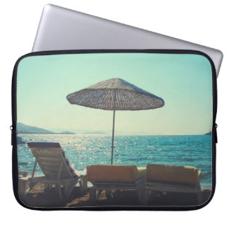 Sandy beach on a sunny afternoon,  with parasols a laptop sleeve