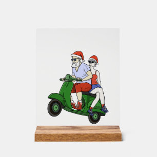 Santa and Mrs. Claus riding a scooter Acrylic Sign