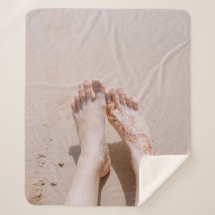 Selective focus photography of feet with tattoo on sherpa blanket