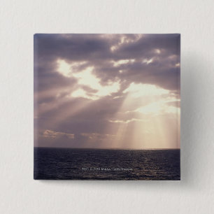 Setting sun shining through clouds over ocean 2 inch square button