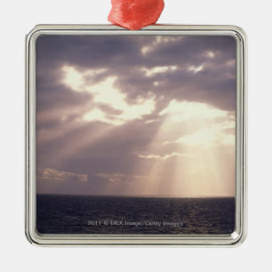 Setting sun shining through clouds over ocean metal ornament