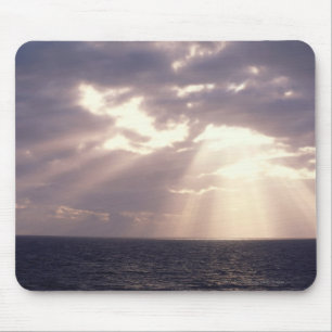 Setting sun shining through clouds over ocean mouse pad