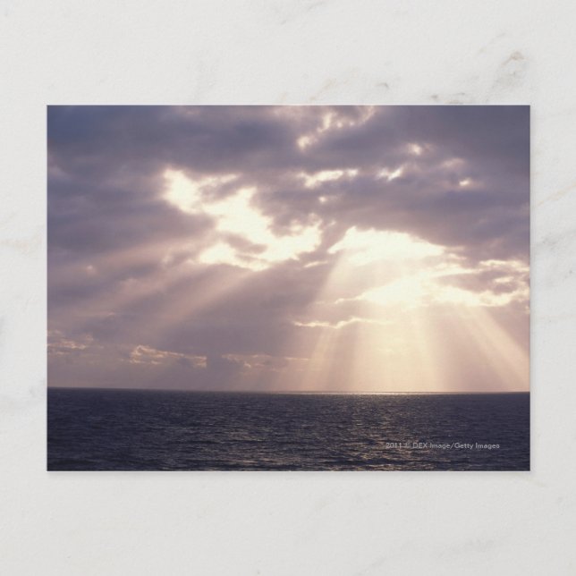 Setting sun shining through clouds over ocean postcard (Front)