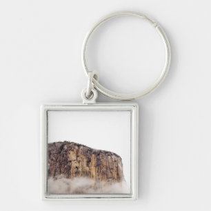 Sheer cliff rising above clouds keychain