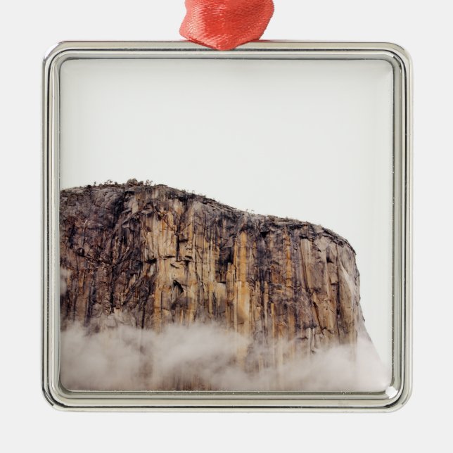 Sheer cliff rising above clouds metal ornament (Front)
