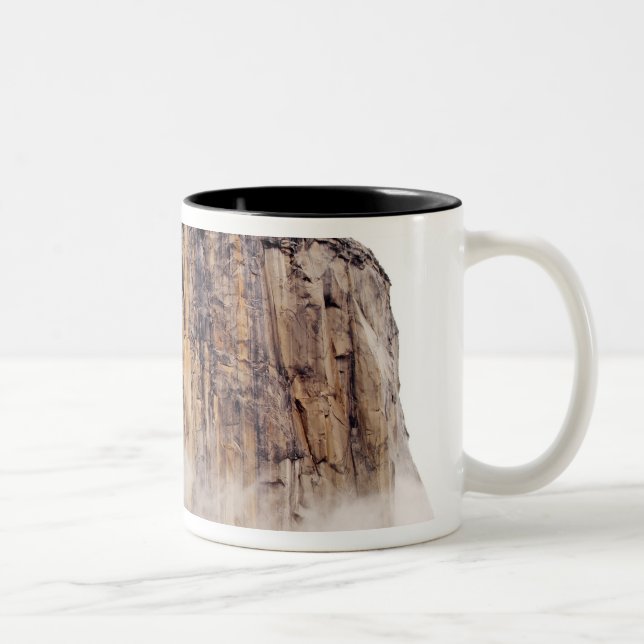 Sheer cliff rising above clouds Two-Tone coffee mug (Right)