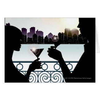 Silhouette of a couple toasting martini glasses
