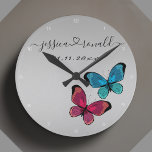 Silvery Grey Names Date Wedding Gift Personalized Round Clock<br><div class="desc">Beautiful connected by love silvery grey wall clock celebrating a couple and their love. Personalized with the couple's names written in cursive script and connected with a swirly heart. It's additionally personalized with a custom date. Decorated with a cute illustration of two butterflies, one purple one blue. Trendy, modern, and...</div>