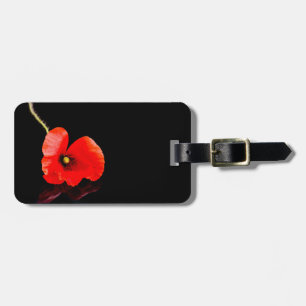 Single red poppy on black luggage tag