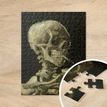 Skeleton with Burning Cigarette | Vincent van Gogh Jigsaw Puzzle<br><div class="desc">Skull of a Skeleton with Burning Cigarette (1886) by Vincent van Gogh is a striking and unconventional still-life painting that features a human skull with a lit cigarette between its teeth. The dark background enhances the starkness of the skeletal figure, while the small plume of smoke adds a sense of...</div>