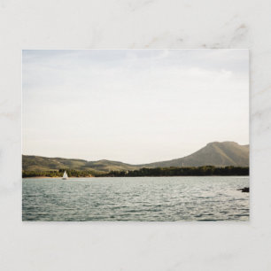 Small ship sailing on a lake at the afternoon postcard
