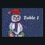 Smiling Snowman Holding String of Christmas Lights Table Number<br><div class="desc">This table number card for your parties or events has a smiling snowman with a carrot nose wearing a winter blue and red hat and scarf holding a lit string of colourful Christmas lights on a dark blue background with falling snow.  Customize your table number with the template.</div>