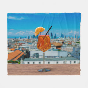 Spritz cocktail on a table with view of Milan Fleece Blanket