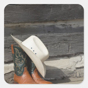 Sticker Carré Casquette Cowboy sur bottes de cowboy devant un ca