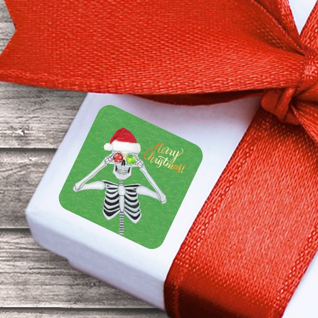 Sticker Carré Smiling Noël Squelette Ornament Eyes on Green (Funny Merry Christmas Skeleton ornament eyes Santa Hat on green with gold flecks paper sticker.)