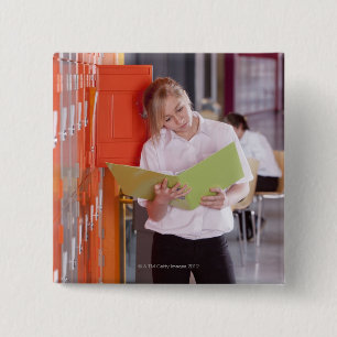 Student removing binder from school locker 2 inch square button