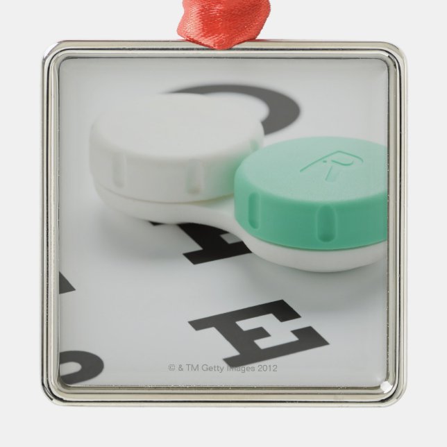 Studio shot of contact lens case on eye chart metal ornament (Front)