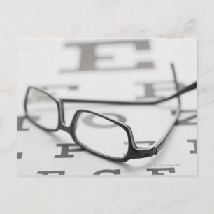 Studio shot of eyeglasses on eye chart postcard