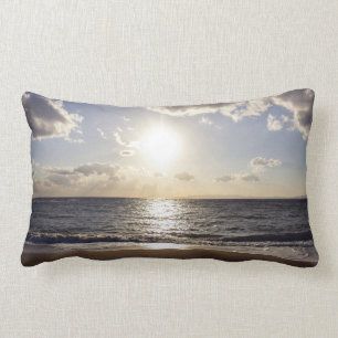 Sun pierces the blue sky on a deserted beach lumbar pillow
