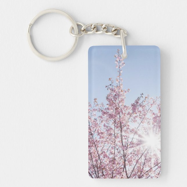 sun rays pass through pink flowers of a wow tree keychain (Front)