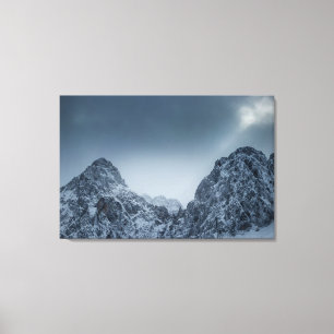 Sunlight and dark clouds over snowy mountains canvas print