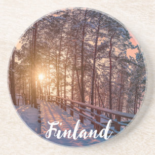 Sunset in snowy pine forest with sun ray coaster