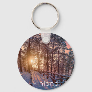 Sunset in snowy pine forest with sun ray keychain