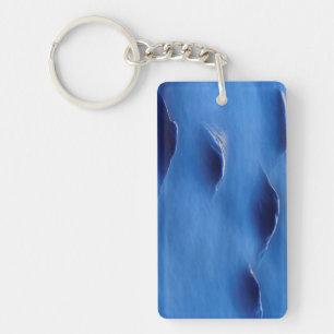 Sunset on rocks protruding through foamy water keychain