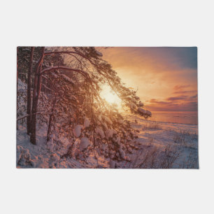 Sunset over sea and snowy pine tree doormat