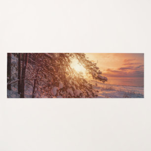 Sunset over sea and snowy pine tree yoga mat