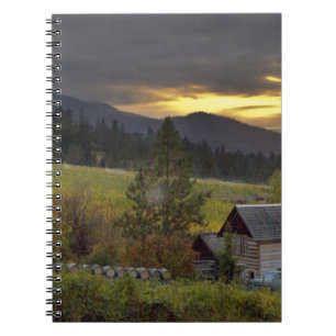 Sunset sky over vineyards and historic log cabin notebook