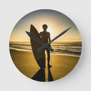 Surfer silhouette during sunrise round clock
