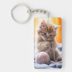 Sweet orange kitten playing with yarn keychain