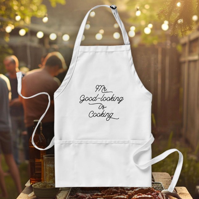 Tablier Fun Chef Humour BBQ M. Le beau est la Cuisine (White apron with "Mr. Good-looking Is Cooking" text hangs in front of a backyard barbecue)