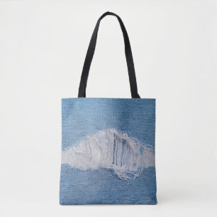 tear of denim texture with a hole and threads show tote bag
