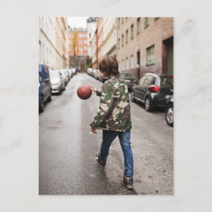 Teenage boy dribbling basketball postcard