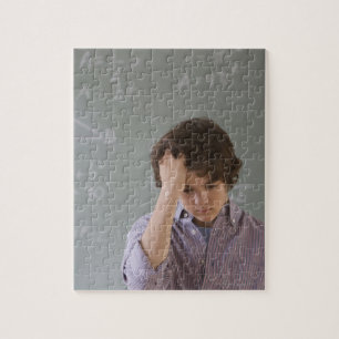 Teenaged boy in front of blackboard with math jigsaw puzzle