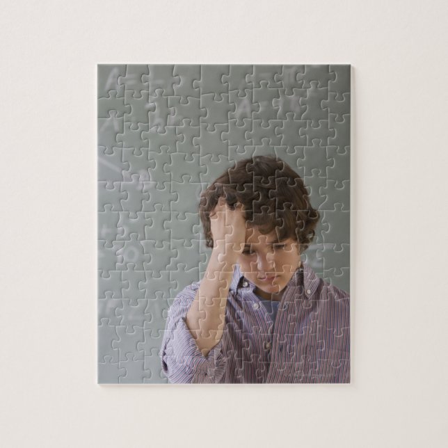 Teenaged boy in front of blackboard with math jigsaw puzzle (Vertical)